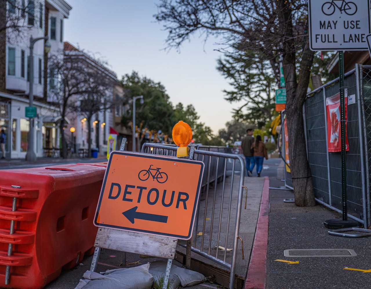 services-03 Street scene featuring a bicycle detour sign and metal railings, guiding traffic.